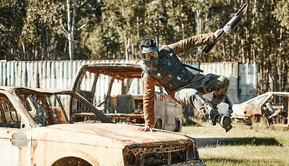 Image showing Paintball game, action and man jump car, agile and run in active battlefield, military playground or training arena. Army mission, gear and person in match competition, conflict or survival challenge