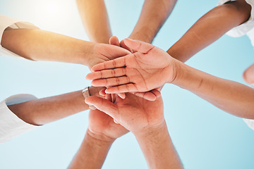 Image showing Circle, low angle and team with hands together for collaboration, unity or support by a blue sky. Teamwork, diversity and group of people in an outdoor huddle for motivation, solidarity or community.