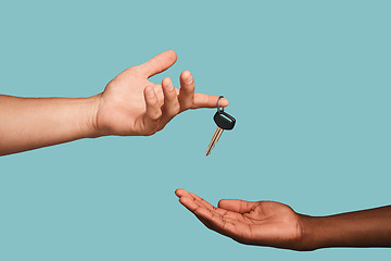 Image showing Hands, key or car dealership with a salesman and customer in studio on a blue background for purchase. Transport, vehicle and deal with an automobile dealer handing keys to a consumer after a sale