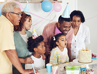 Image showing Birthday, cake and a girl blowing out candles while celebrating with her black family in their home. Kids, party or celebration with parents, grandparents and children bonding together in a house