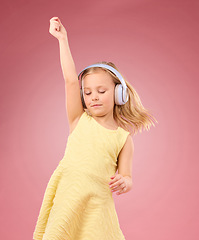 Image showing Music headphones, dance and girl kids in studio, pink background or color backdrop for happiness. Happy children, dancing and listening to radio, audio and sound with energy, fun songs and freedom