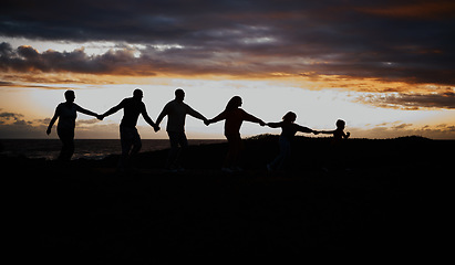 Image showing Sunset, beach and silhouette of family with children by ocean for bonding, quality time and peace. Shadow, nature and grandparents, parents and kids holding hands on vacation, holiday and weekend