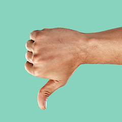 Image showing Hand, thumbs down and negative emoji with a man in the studio on a green background for disagreement. Gesture, no and negativity with a male indoor to disagree, vote or voice his review and feedback