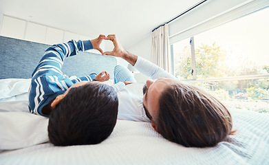 Image showing Heart shape, father and son on bed, quality time and happiness on break, relax and bonding together. Family, dad and boy in bedroom, sign for love and resting with joy, carefree and loving in morning