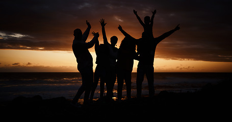 Image showing Freedom, sunset and silhouette of people at the beach while on a summer vacation, adventure or weekend trip. Carefree, happy and shadow of group of friends having fun together by the ocean on holiday