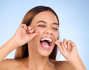 Image showing Dental floss, tooth cleaning and woman smile with teeth hygiene, healthcare and wellness treatment. Isolated, blue background and studio with a female feeling beauty from a clean mouth with self care