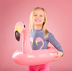 Image showing Safety, happy and portrait of girl and pool float for swimming, summer break and relax. Youth, funny and inflatable with child and flamingo ring for pool, smile and beach holiday on pink background