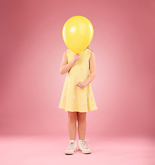 Image showing Balloon cover face, girl and child in studio isolated on a pink background mockup. Children, birthday party and celebration event with young shy kid hiding with yellow air ballons and inflatable.