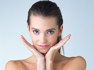 Image showing Woman, makeup and hands on face in studio for skincare, wellness or cosmetics on blue background. Portrait, beauty and girl model with dermatology, satisfaction or luxury skin routine while isolated