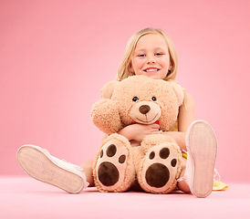 Image showing Teddy bear love, girl and portrait with a soft toy with happiness and care for toys in a studio. Isolated, pink background and a young female child feeling happy, joy and cheerful with stuffed friend
