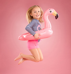 Image showing Jump, smile and portrait of girl and pool float for swimming, summer break or happiness. Youth, funny and inflatable with child and flamingo ring for cute, happy or beach holiday on pink background