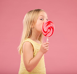 Image showing Candy, sweets and lollipop with girl in studio for sugar, party and carnival food isolated on pink background. Cute, positive and youth with child and eating colorful snack for playful and treats