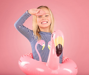 Image showing Safety, smile and portrait of girl and pool float for swimming, summer break or happiness. Youth, funny and inflatable with child and flamingo ring for pool, smile or beach holiday on pink background