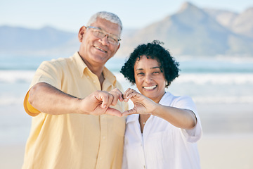 Image showing Hands, heart and a senior couple on the beach together during summer for love, romance or weekend getaway. Portrait, travel or emoji with a mature man and woman bonding outdoor on sand by the coast