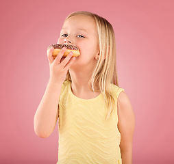 Image showing Portrait, girl kid and donuts on pink background, studio and color backdrop for dessert, sweet round treat and sugar. Happy young child eating doughnut, baked snack and delicious pastry of junk food