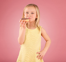 Image showing Portrait, girl child and donuts on pink background, studio and color backdrop for dessert, sweet treat and sugar. Happy young kid eating doughnut, baked snack and delicious round pastry of junk food