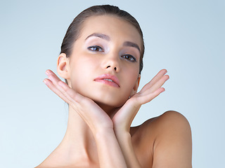 Image showing Makeup, woman and hands on face in studio for skincare, wellness or cosmetic on blue background. Portrait, beauty and girl model with dermatology, satisfaction or luxury skin routine while isolated