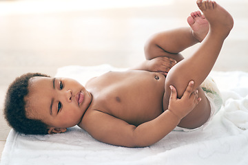 Image showing Calm, cute and baby on a bed with a diaper, relax and curious while looking at feet at home. Black child, infant and adorable boy on a changing table, comfortable and relaxing alone in a nursery