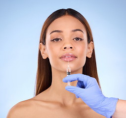 Image showing Portrait, lips and injection of woman on studio, blue background and facial beauty. Young female model, lip filler and needle for plastic surgery, skincare transformation and aesthetic face change