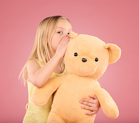 Image showing Teddy, secret and young girl talking and whispering to a toy bear in a studio. Playing, child and bonding with love and care for toys with isolated pink background in a happy discussion together