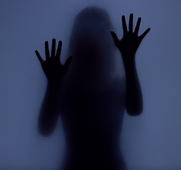 Image showing Shadow, glass and hands with a woman in studio on a blue background for mystery or sensual secrecy. Creative, silhouette and window with a female posing for beauty, art deco or feminine desire