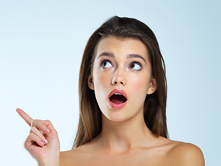 Image showing Wow, pointing and beauty woman isolated on blue background for sale, discount or makeup promotion deal. Surprise face of cosmetics model or young person in studio showing mockup or product placement