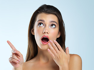 Image showing Wow, shocked and pointing woman isolated on blue background beauty sale, discount or makeup promotion. Surprise face of cosmetics model or gossip person in studio showing mockup or product placement