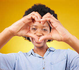 Image showing Love, heart hands sign and portrait of black woman, smile and kindness isolated on yellow background. Motivation, support and loving hand gesture, happy African model in studio with caring mindset.