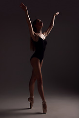 Image showing Ballet, woman and dancer with routine, fitness and training for performance on a dark studio background. Female performer, lady and ballerina with wellness, focus and commitment for art or creativity