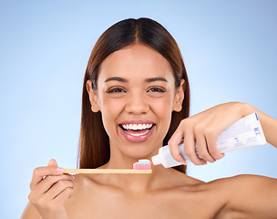 Image showing Portrait, toothbrush and dental with a model woman in studio on a blue background for oral hygiene. Mouth, cleaning and smile with an attractive young female brushing her teeth for whitening