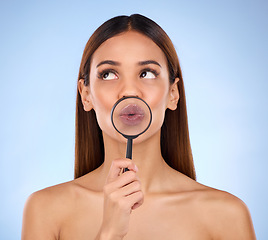 Image showing Pouting, skincare and a woman with a magnifying glass on mouth isolated on a blue background. Goofy, thinking and a girl with a tool for a closeup on lips, beauty and cosmetics on a backdrop