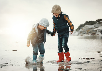 Image showing Beach, boots and children in water together, holding hands and playing in waves with smile. Fun, holiday and brothers, happy boys on ocean vacation at sunset, jumping and splash on evening sea walk.