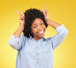 Image showing Goofy, happy and portrait of a black woman in a studio with a silly, funny and comic gesture. Happiness, smile and African female model with peace sign for bunny ears on her head by yellow background