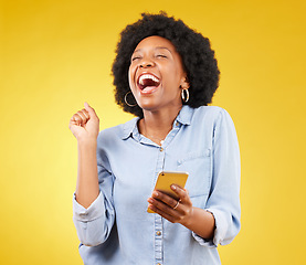 Image showing Happy, excited and phone with black woman in studio for text message, notification and social media news. Deal, winner and celebration with girl on yellow background for offer, giveaway and surprise