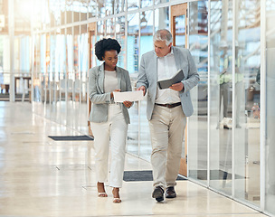 Image showing Teamwork, man and black woman in office, walking and discussion for report, schedule and planning. Employees, coworkers and consultants with documents, notebook and check information in workplace