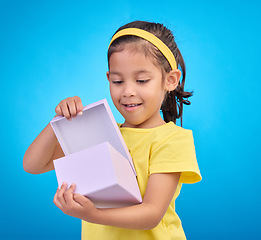 Image showing Box, surprise and child with gift in studio on blue background for present, birthday or celebration. Happiness, smile and isolated young, excited and happy girl opening package, product and parcel