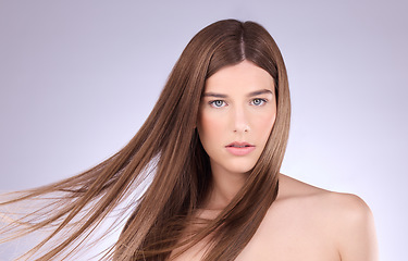 Image showing Portrait, hair and windy with a model woman in studio on a gray background for haircare or keratin treatment. Shampoo, salon and beauty with an attractive young female posing in a breeze on a wall