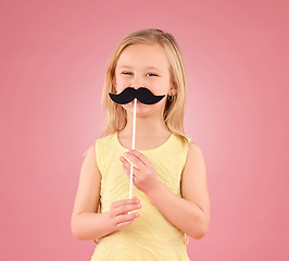 Image showing Girl, child and portrait in studio with moustache prop on a pink background with a smile and stick. Female kid model with happiness, creativity and comic icon in hand isolated on a color and space