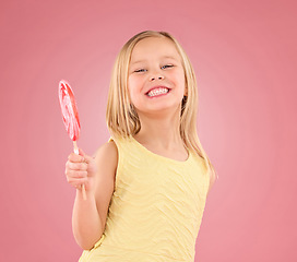 Image showing Candy, smile and lollipop with portrait of girl in studio for sugar, party and carnival food isolated on pink background. Cute, positive and youth with child and eating snack for playful and treats