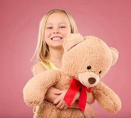 Image showing Teddy bear hug, girl smile and portrait with a toy with happiness and love for toys in a studio. Isolated, pink background and a young female child feeling happy, joy and cheerful with stuffed friend