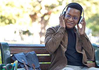 Image showing Black man, relax or headphones on park bench, nature garden or college campus for university, school or study break. Smile, happy or student listening to music, radio or learning podcast for homework