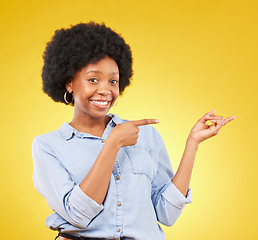 Image showing Happy, portrait of a black woman in studio pointing at mockup space for advertising or marketing. Happiness, smile and African female model showing mock up for product placement by yellow background.