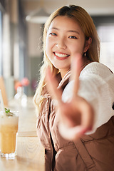 Image showing Peace, hand gesture and portrait with an asian woman in a coffee shop, drinking a beverage or refreshment. Face, emoji and cafe with an attractive young female enjoying a smoothie or juice drink