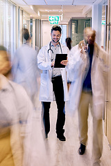 Image showing Digital tablet, happy and man doctor walking in a busy hospital, excited while checking online schedule. Motion blur, male and healthcare expert with app for planning, communication and prescription
