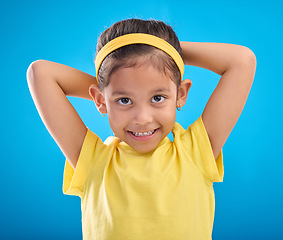 Image showing Young girl, portrait and studio with a student feeling happy with a smile and blue background. Isolated, cute and adorable child face in a yellow outfit with happiness, joy and cheerful smiling