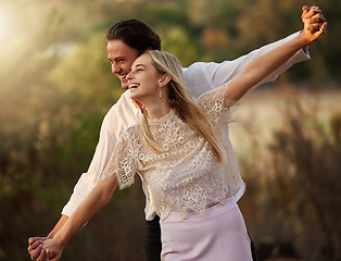 Image showing Nature, romance and couple with playful freedom on romantic honeymoon or summer date. Love, woman and man holding hands, flying gesture and happy smile bonding together on weekend at sunset in forest