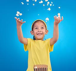 Image showing Food, happy and child throw popcorn on blue background for entertainment, movies and cinema mockup. Comic, smile and excited young girl with sweet snack in studio for party, celebration and eating