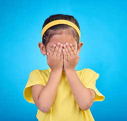 Image showing Cover eyes, hands on face and child on blue background for shy, mistake expression and sad in studio. Emotion reaction, childhood and young girl isolated for hide and seek, surprise and blind emoji