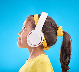 Image showing Music, headphones and listening with girl in studio for streaming, mobile radio and audio. Technology, media and youth with profile of child isolated on blue background for natural, happy and songs