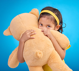 Image showing Portrait, hug and child in studio with teddy bear, sweet and innocent on gradient blue background. Face, embracing and child with teddy. hiding and shy, sweet and play while hugging on isolated space